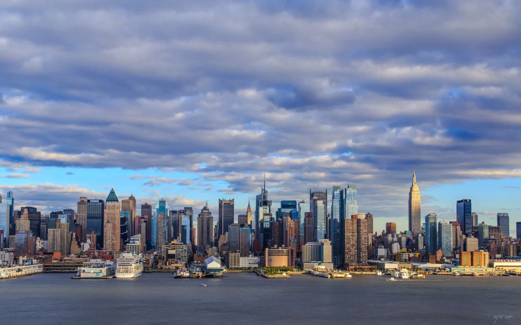 New York City skyline skyscrapers Hudson River sunset clouds urban landscape