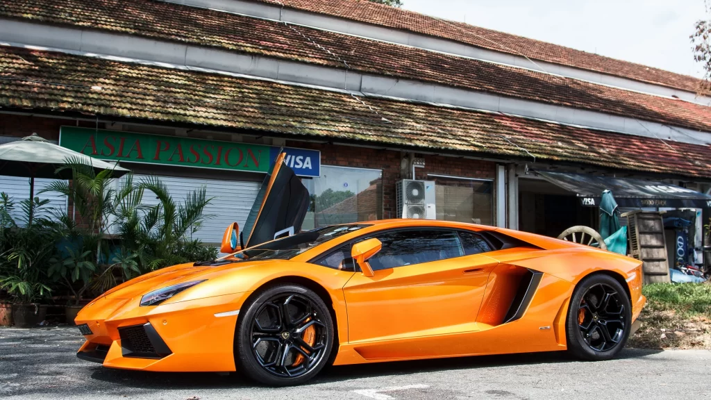 Sports car orange luxury wheels building greenery
