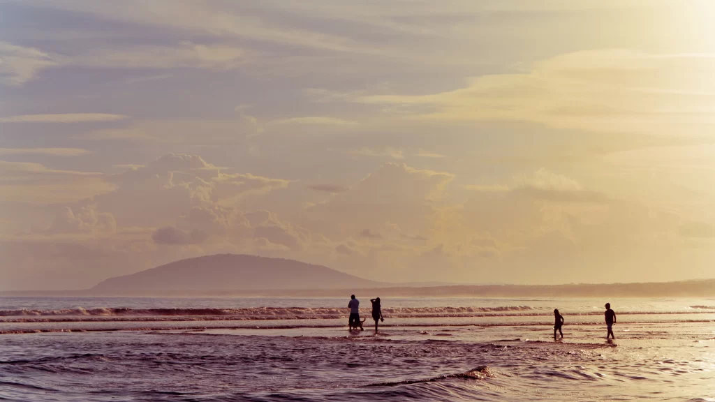 Sunset beach people waves sky clouds
