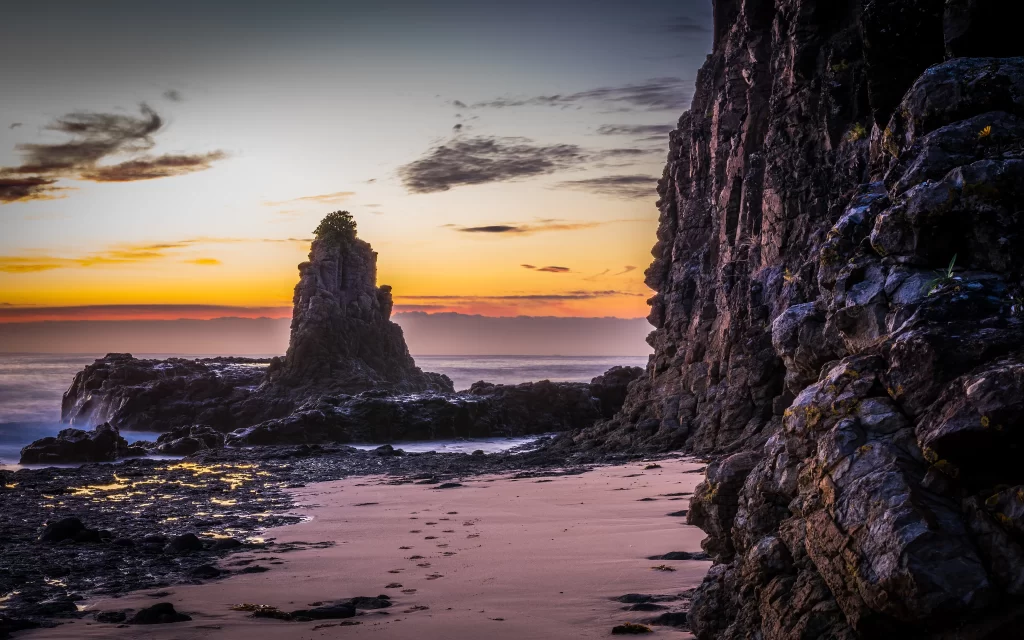 Sunset beach rock formations ocean sky clouds