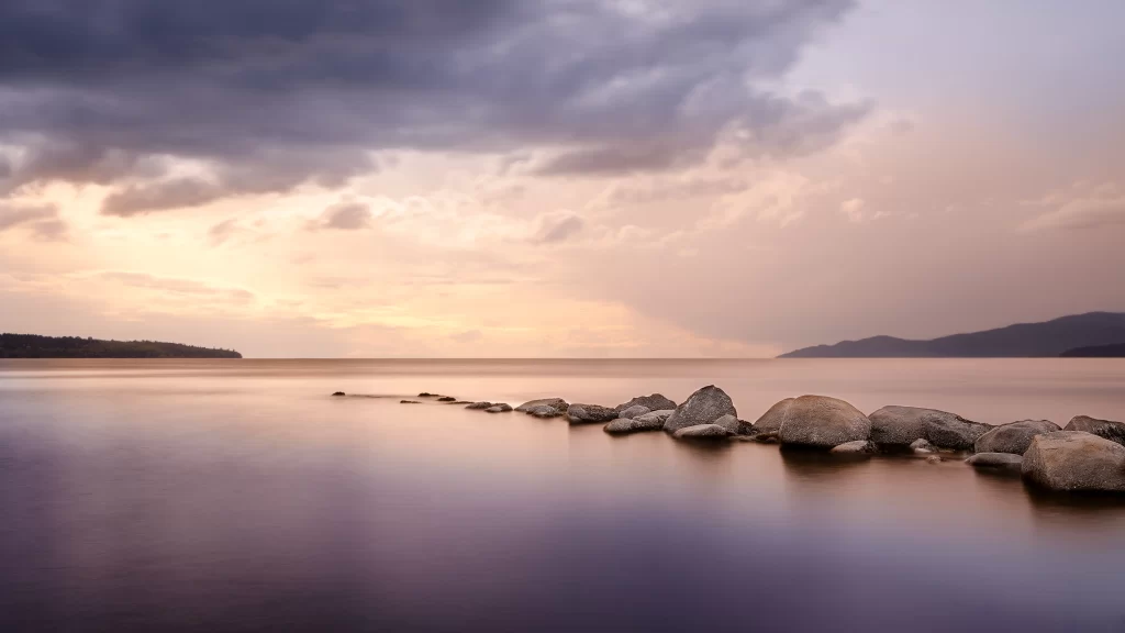 Sunset calm water rocks clouds landscape