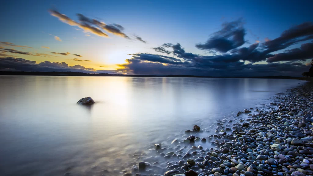 Sunset calm water sky clouds pebbles