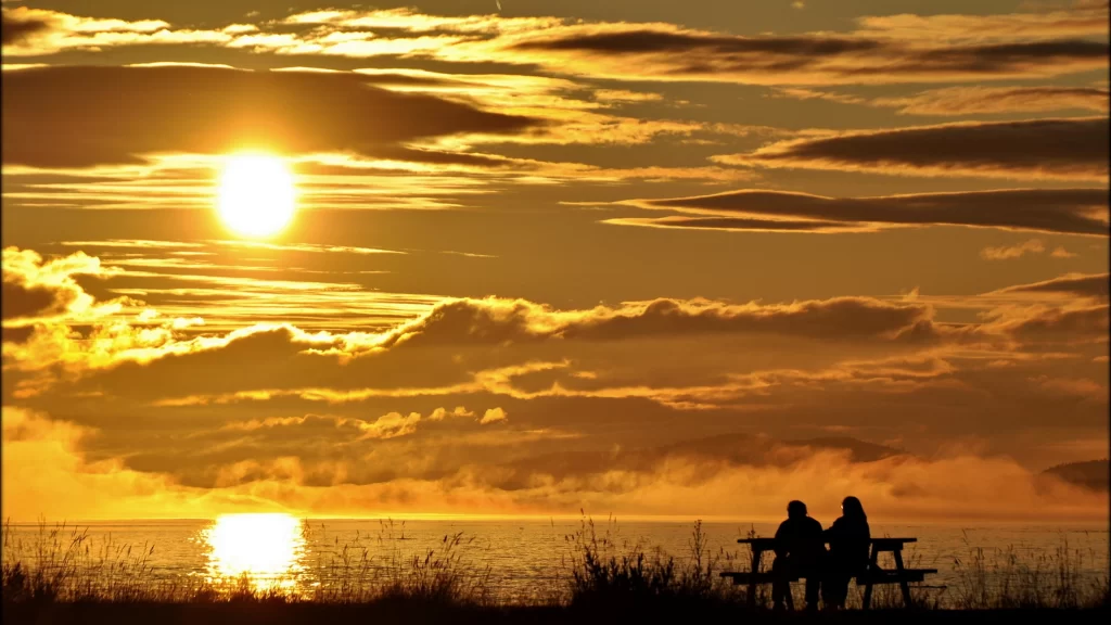 Sunset clouds sea bench couple reflection