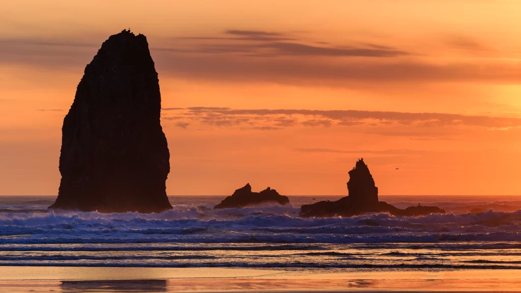 Sunset ocean rock formations waves beach sky