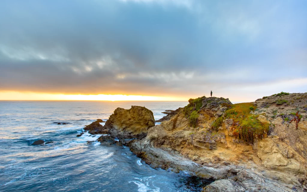 Sunset ocean rocky shore clouds horizon tranquil