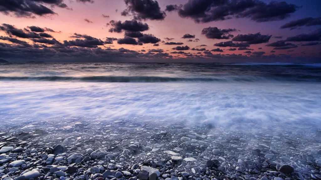 Sunset ocean waves pebbles clouds sky