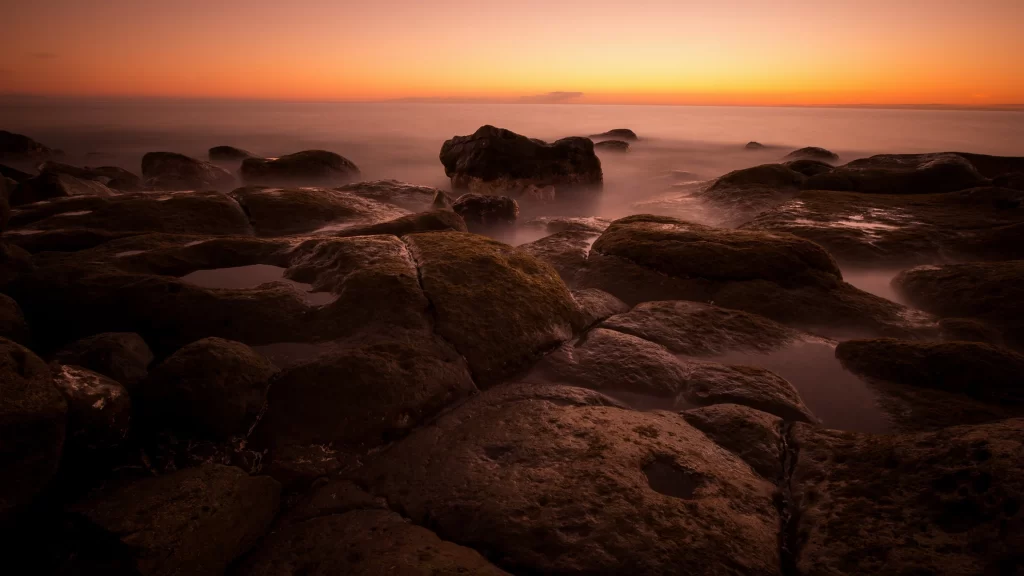 Sunset rocks ocean horizon mist tranquil