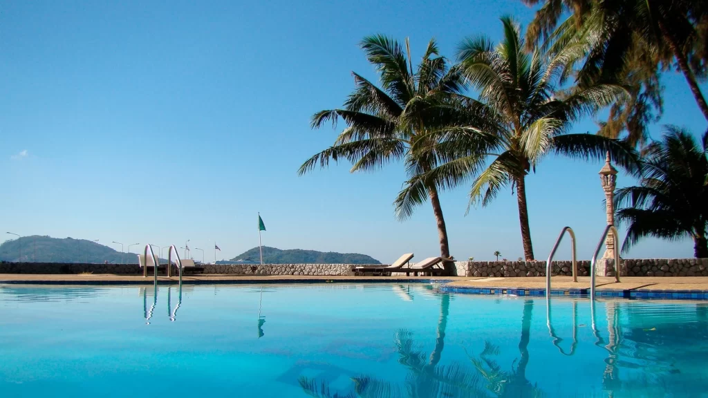 Swimming pool palm trees clear sky lounge chairs mountains blue water