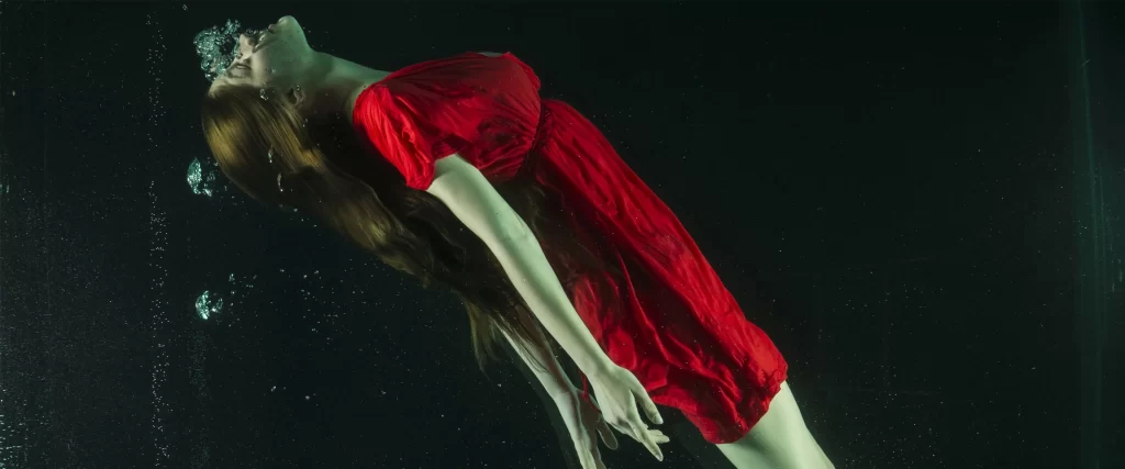 Underwater woman red dress bubbles serene