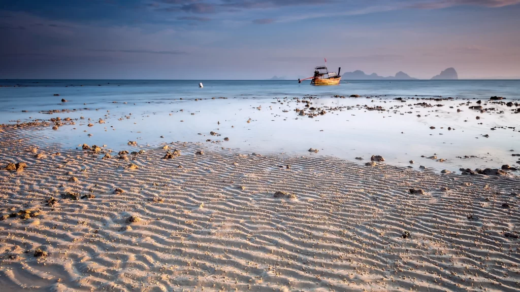 beach boat ocean sunset sand rocks