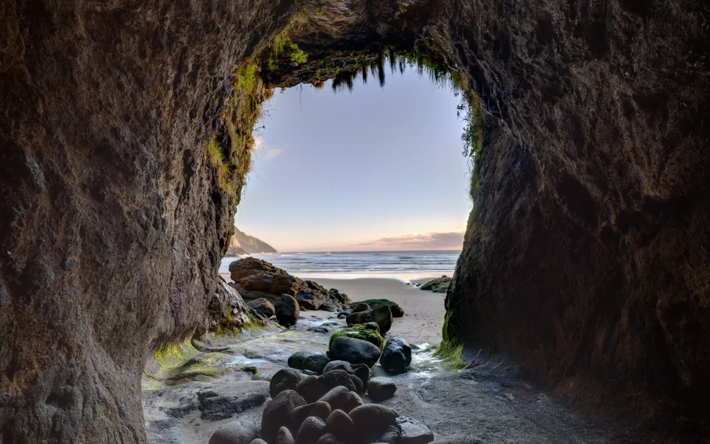 beach cave ocean rocks sunset