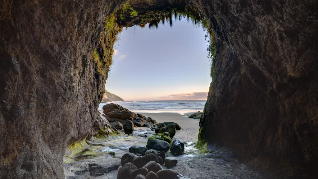 beach cave ocean rocks sunset