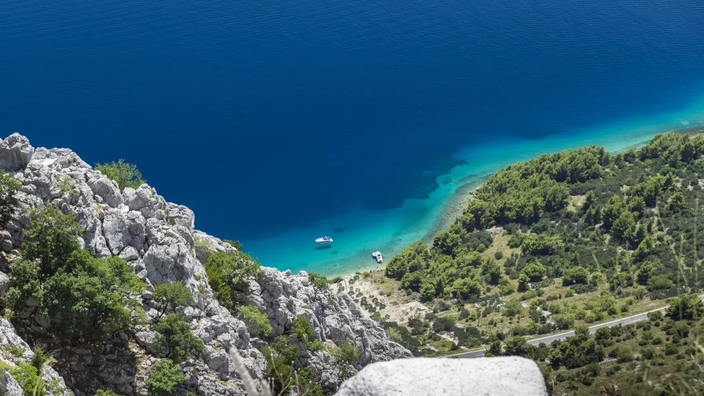 beach ocean boat greenery rocks coastline blue nature