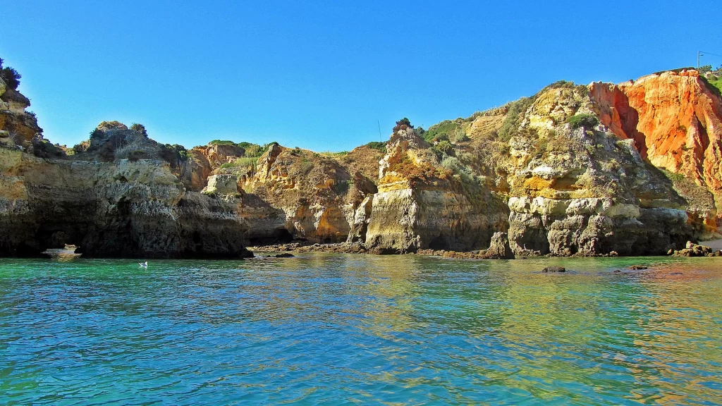 beach ocean cliffs rocks clear water blue sky