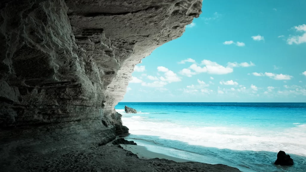 beach ocean rock cave sky clouds