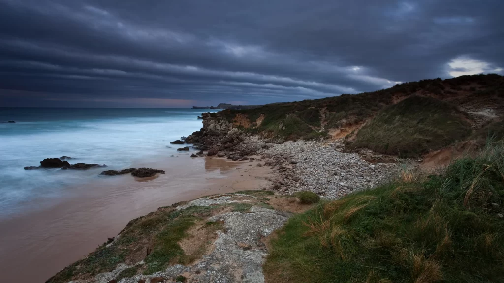 beach ocean rocks clouds grass sky