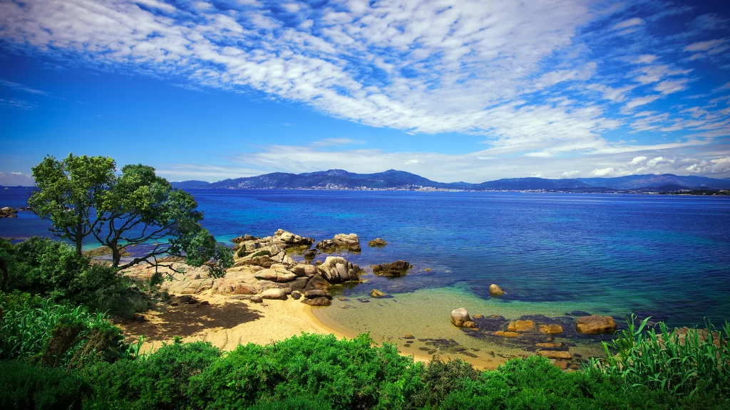 beach ocean rocks sky clouds greenery
