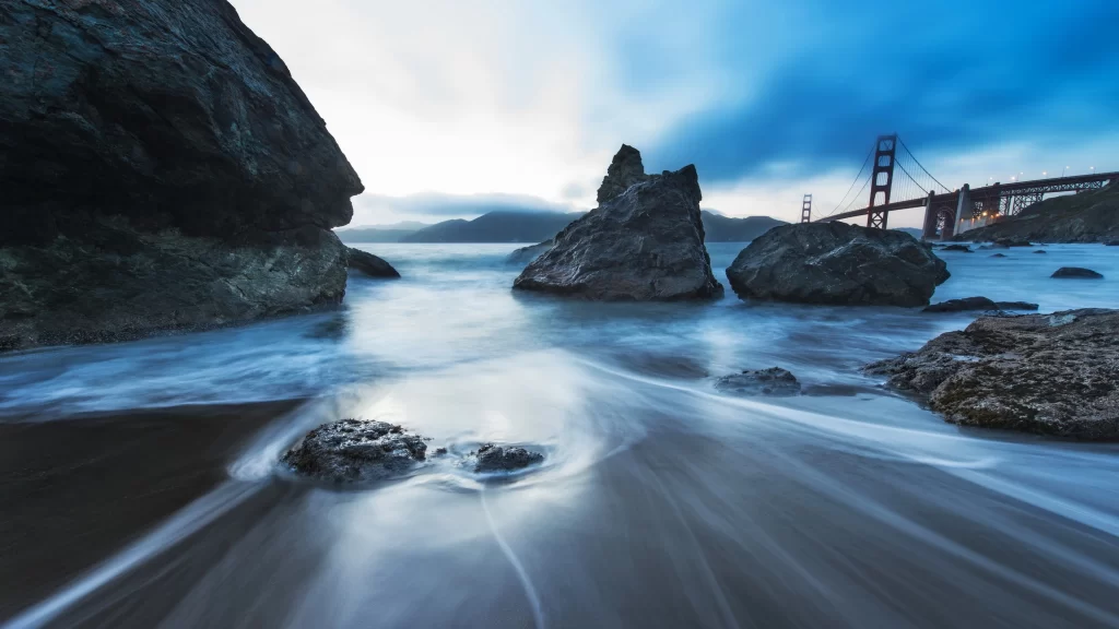 beach rocks water bridge sky