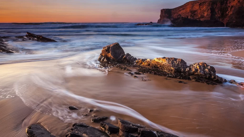 beach sunset rocks waves sky cliffs
