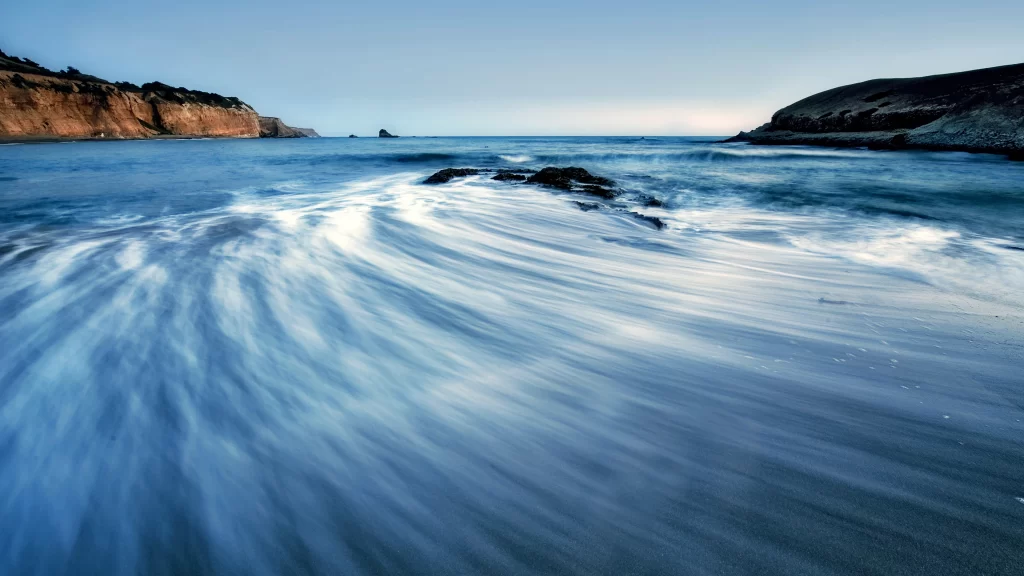 beach waves cliffs sky water motion