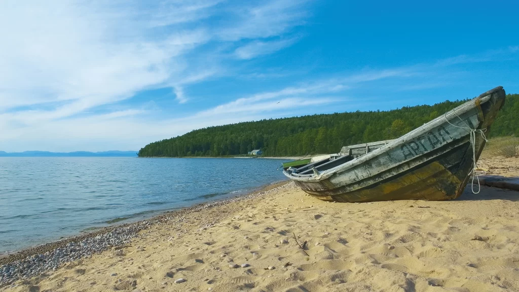 boat beach water sky trees clouds