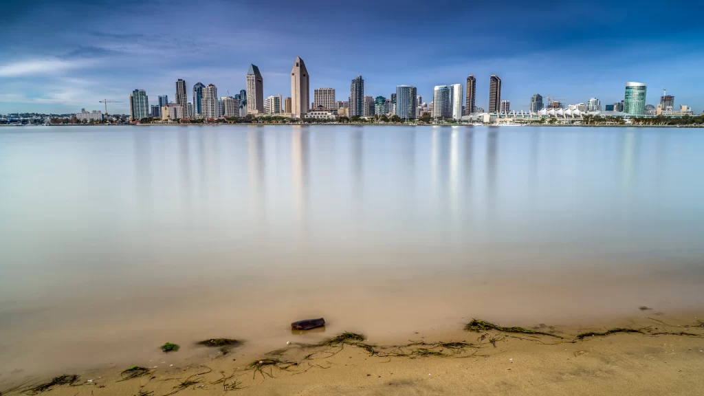 city skyline water reflection calm urban blue sky sandy shore tranquil architect
