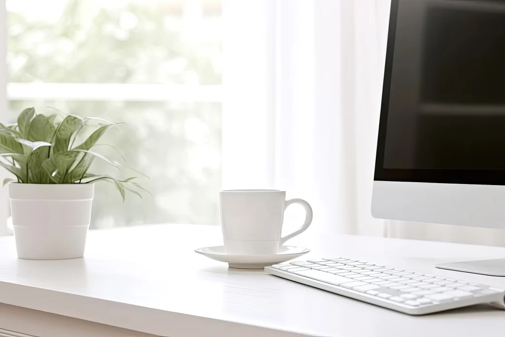 Clean Minimalist Workspace with Computer and Coffee Cup on White Desk
