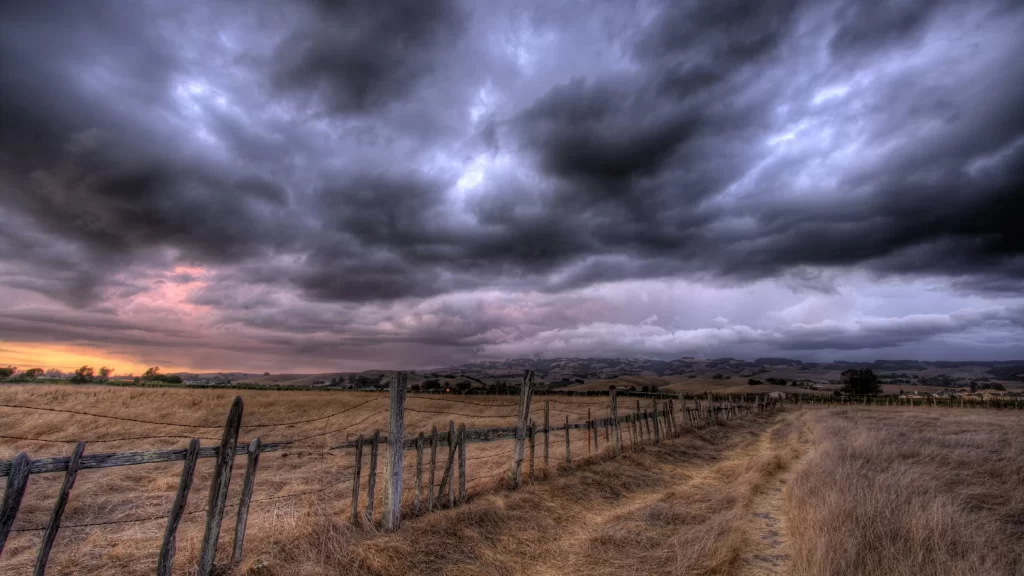 cloudy sky rural landscape wooden fence dry grass sunset dramatic weather