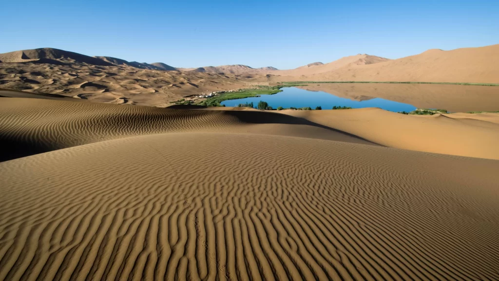 desert sand dunes oasis water blue sky