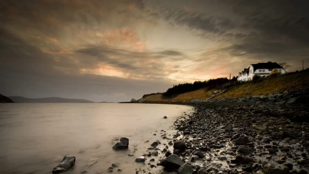 house rocky shore sunset clouds calm water landscape