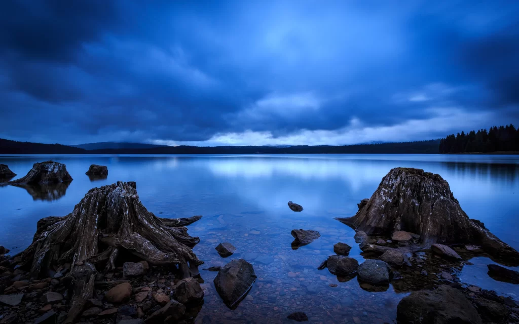 lake sky clouds reflection rocks trees