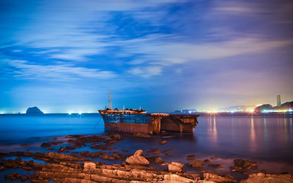 Abandoned Ship Rocky Shoreline Twilight Cityscape Reflection