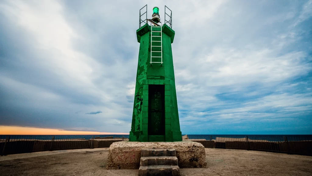 lighthouse green ocean sky clouds sunset