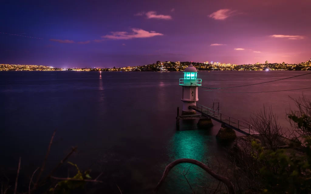 lighthouse night water city lights sky