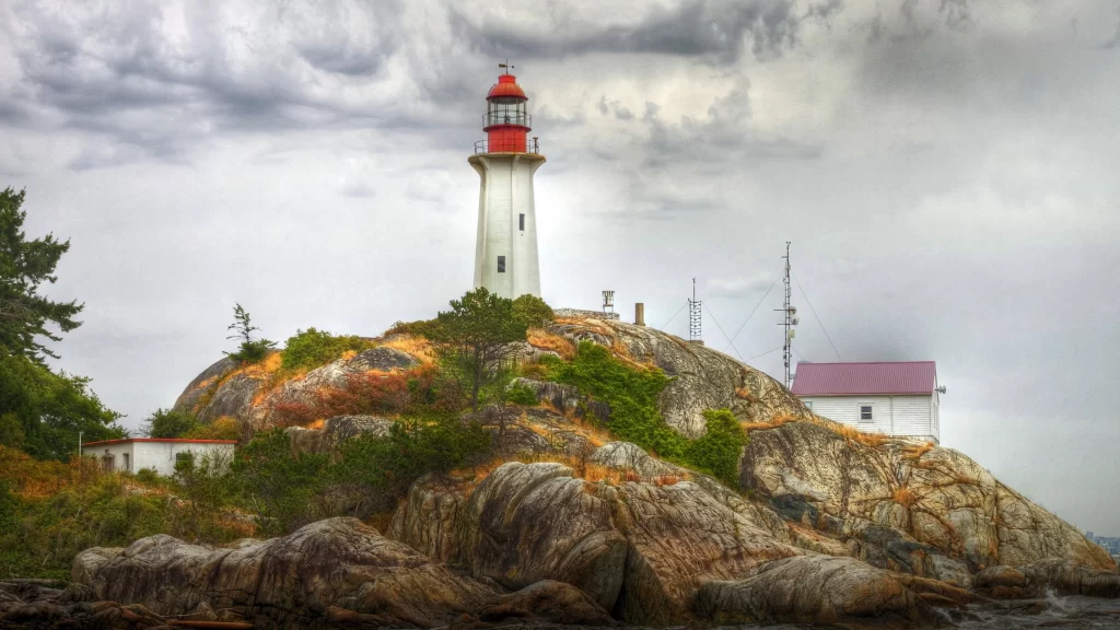 lighthouse rocky landscape cloudy sky vegetation