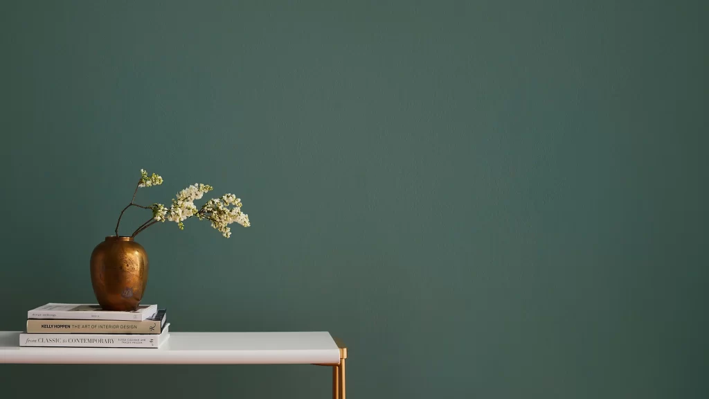 Minimalist Home Decor with Brass Vase and Books Against Green Wall
