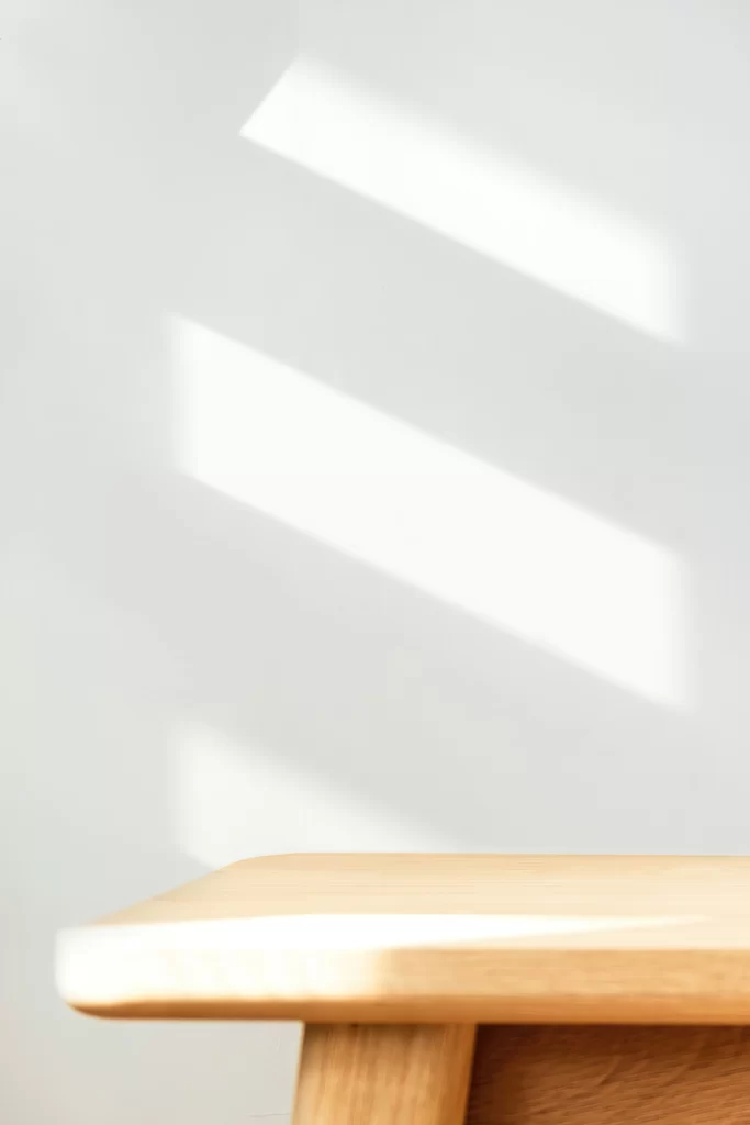Minimalist Wooden Stool with Window Blind Shadows on White Wall