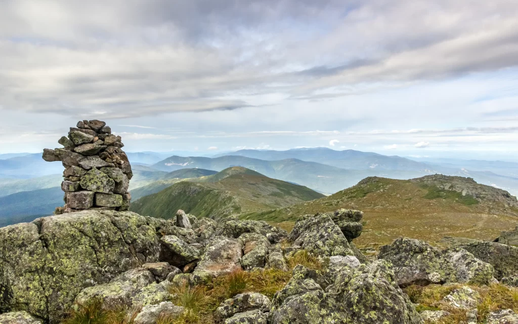 mountain landscape rocky terrain cairn cloudy sky greenery