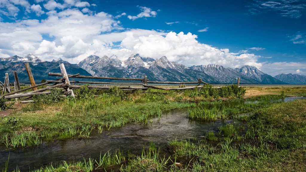 mountains grass water sky clouds fence
