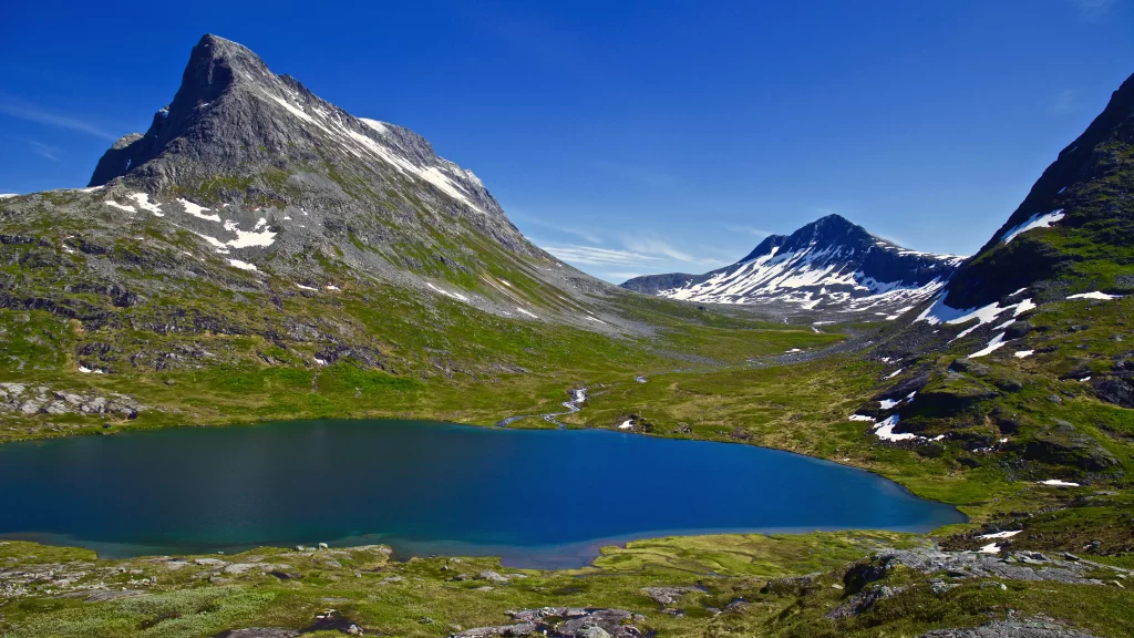 mountains lake green grass snow blue sky