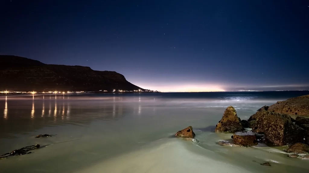 night beach calm water stars sky