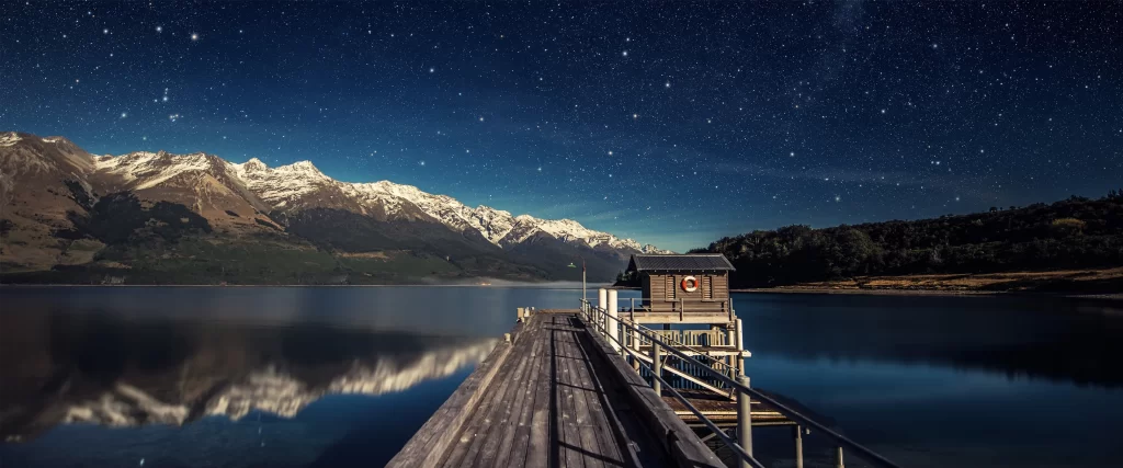 night sky stars lake mountains dock cabin