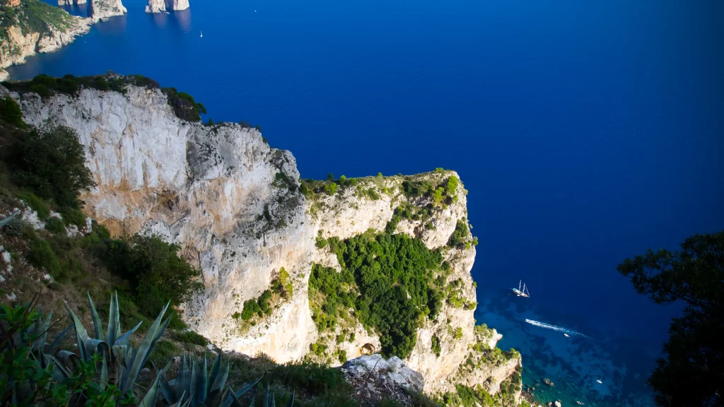 ocean cliffs boat greenery blue water
