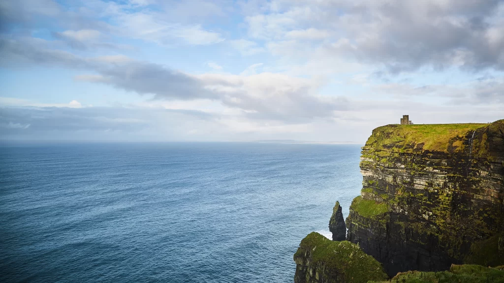 ocean cliffs green grass clouds sky