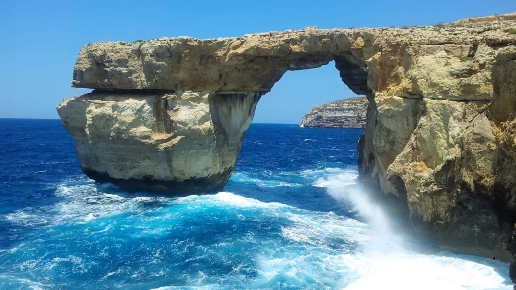 ocean rock arch waves blue sky