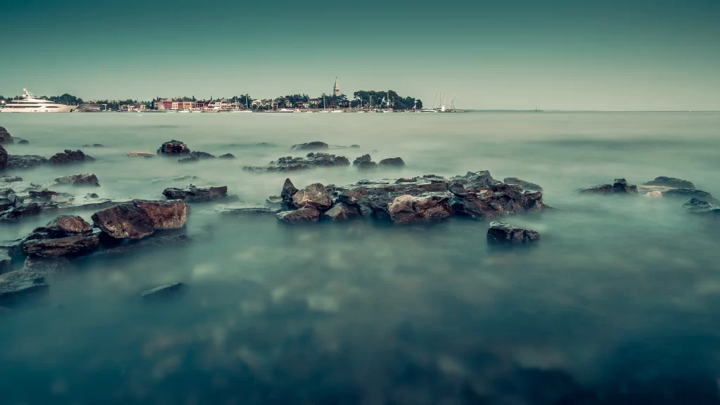 ocean rocks calm water town buildings