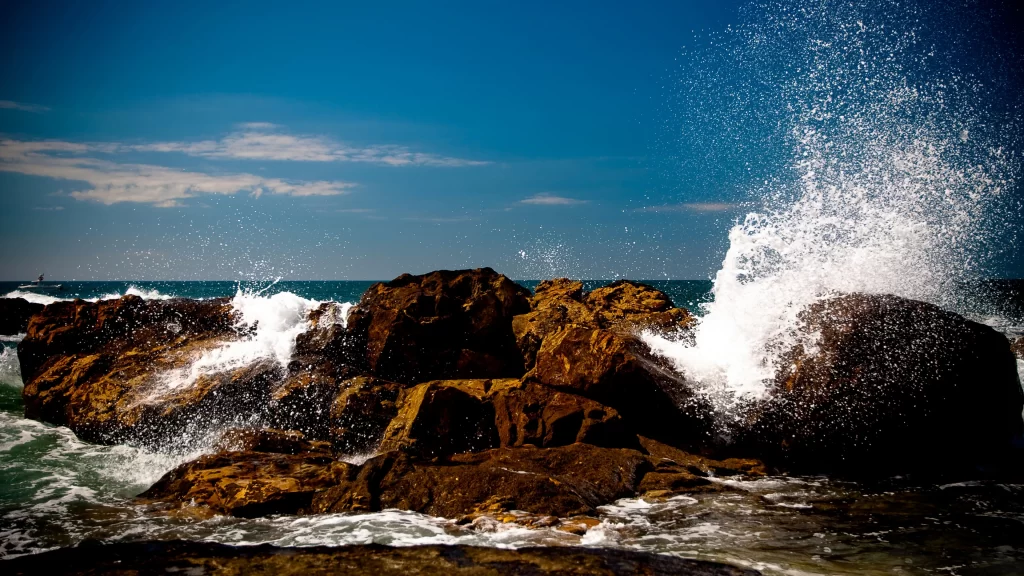 ocean waves rocks splash blue sky