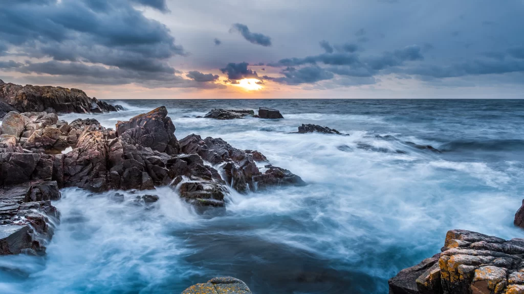 ocean waves sunset rocky shore clouds