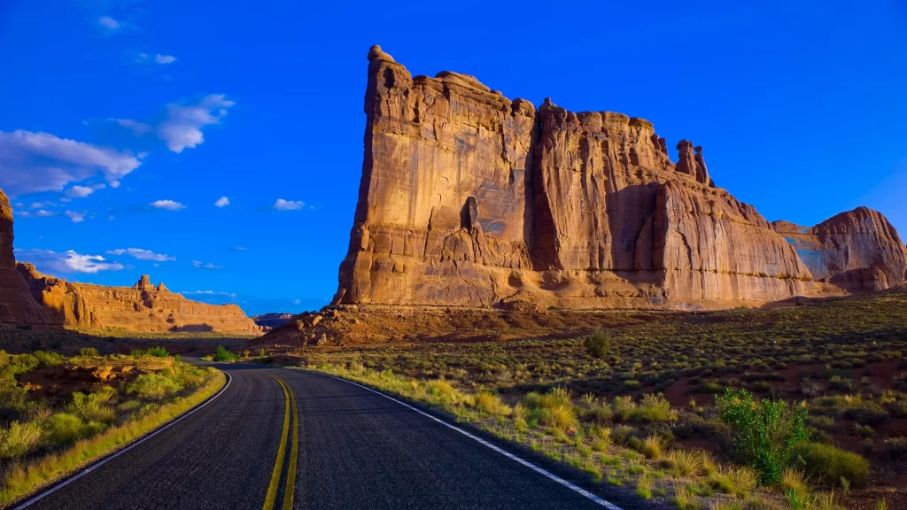 road desert rock formations blue sky vegetation landscape