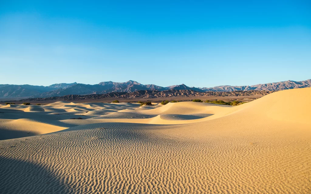 sand dunes desert mountains clear sky